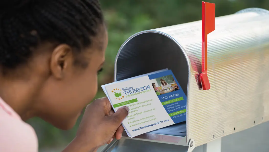 A woman taking a postcard out of her mailbox