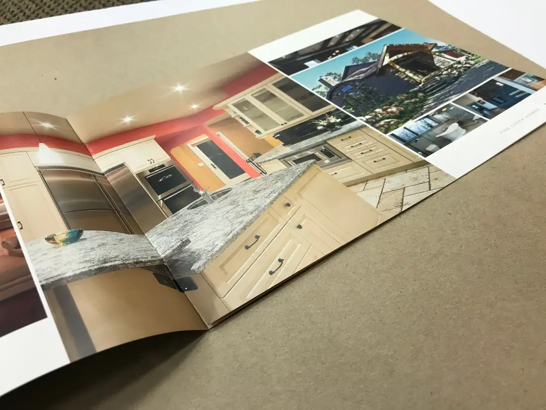 Open saddle-stitched booklet showing a full-bleed kitchen design spread