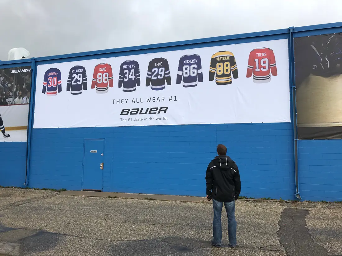 Wall-length Bauer hockey jersey vinyl banner on a building, with a person for scale